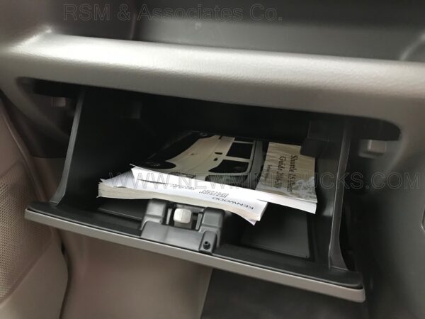 A car compartment with the door open and some papers in it.