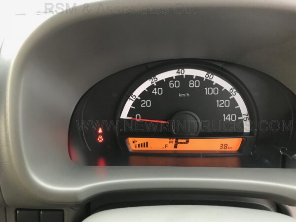 A car dashboard with the speedometer lit up.