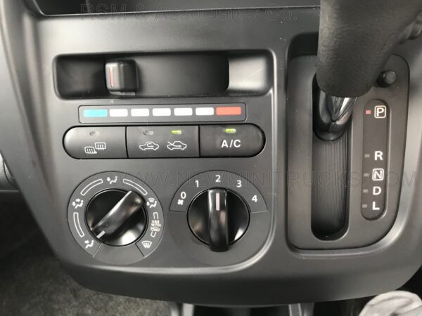 A car dashboard with the air conditioner and temperature controls.