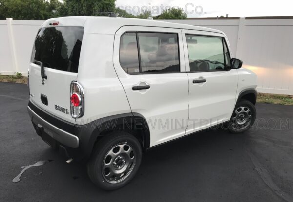 A white suzuki jimny parked on the side of a road.