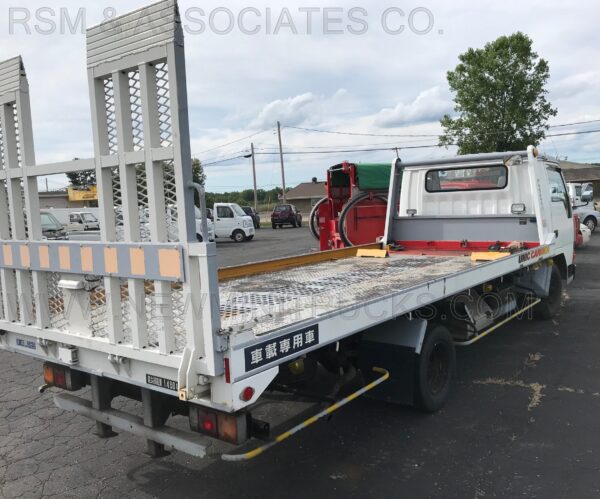 A flatbed truck with a crane on the back of it.