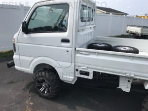 a small white truck with two extra tires